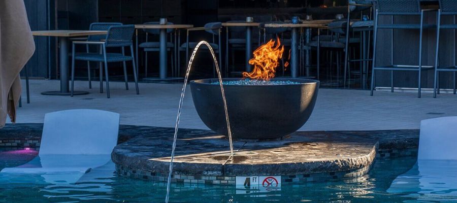 A pool with a fire pit and water feature