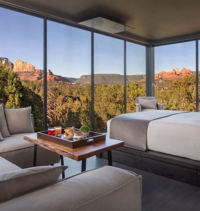 A luxurious room with a large window showing a mountain view, a bed, sofa, and coffee table.