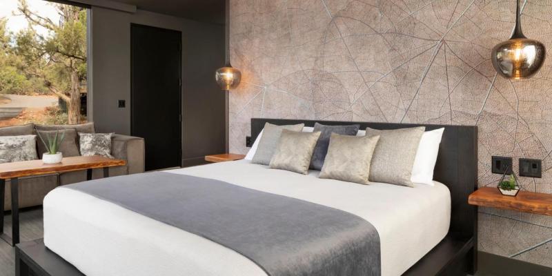 A modern hotel room with a large bed, sofa, and wooden desk